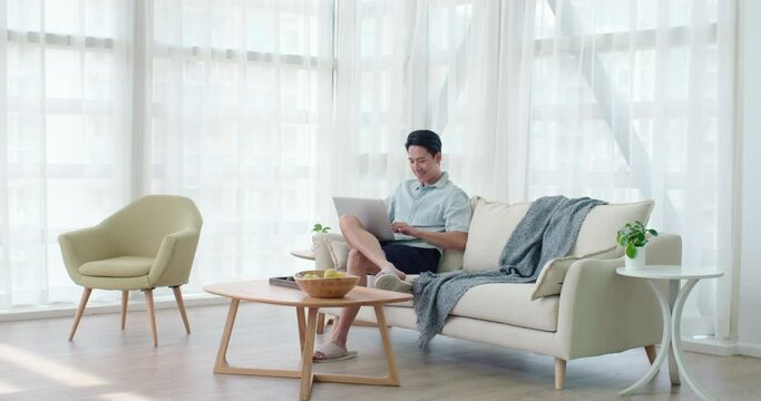 Happy young man using laptop in living room,4K