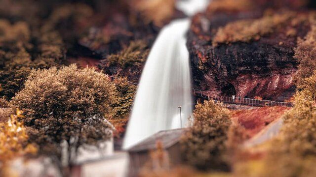 Tilt-shift video of the Steinsdalsfossen waterfall in autumn. People walking on the walkway under the waterfall.