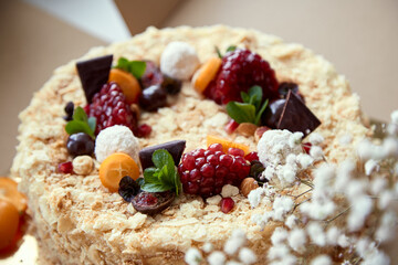 Birthday cake decorated with fruit, pomegranate seeds, chocolate and grapes. Happy holidays and Happy Birthday concept. Top view