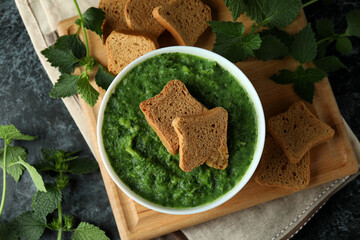 Concept of healthy food with nettle soup on black smokey table