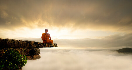 Buddhist monk in meditation at beautiful sunset or sunrise background on high mountain