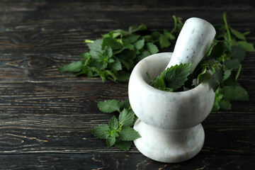 Mortar with fresh nettles on wooden table