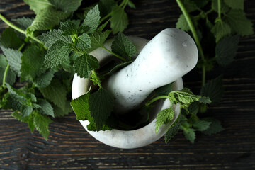 Mortar with fresh nettles on wooden table