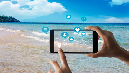 Man using mobile, smart phone play social media with friends on network on sandy beach and blue sea...