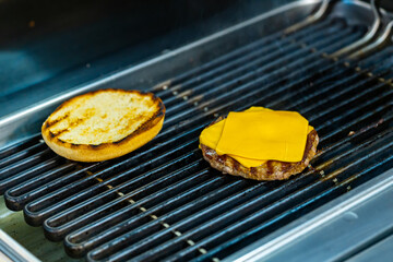 Cheese on cutlet grilling for cheeseburger. Grilling burger on mangal.