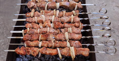 Kebabs preparing on a barbecue grill, shashlik preparing on a mangal, marinated meat preparing on a...