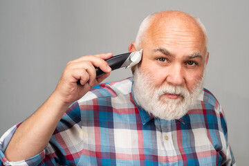 Fototapeta premium Mature man with hair clipper. Old bald man hair clipper, Mature baldness and hair loss concept.