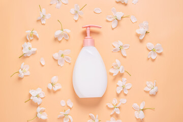 Cosmetic bottle of liquid soap cream for moisturizing and caring for body and face against a background of fresh flowers