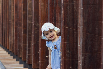 portrait of a cute little girl in lamer Dubai peeking out of the wooden beams