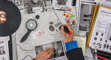 The police detective draws a track on the map of the city and places a tag. - obrazy, fototapety, plakaty