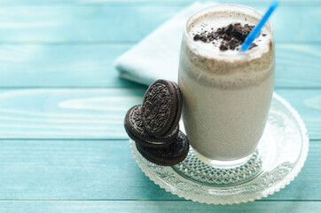 Milkshake (chocolate smoothie)  in a glass on colorful turquoise blue painted wooden boards.