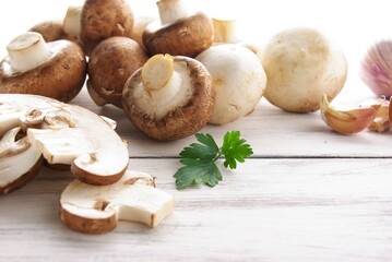 Mushrooms, parsley and garlic on a light wooden table