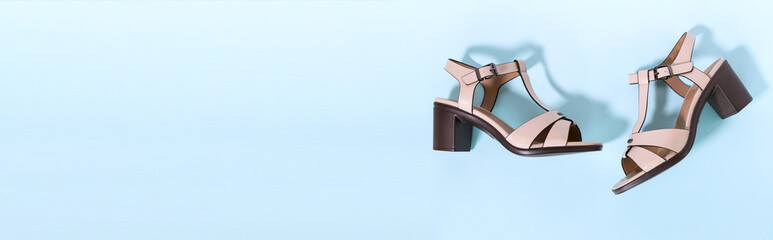 Classic beige women's sandals with medium heels on a blue background. The concept of sales and...