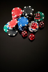 Casino chips and dices on dark reflective background with copy space