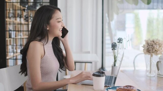 Young Asian woman calling with mobile phone in coffee shop , talking conversation in cafe