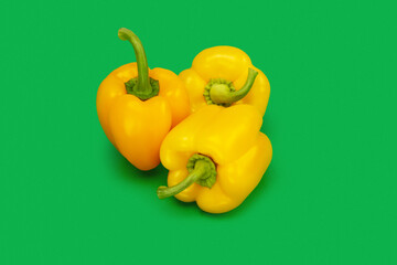 Three yellow bell peppers on a colored background