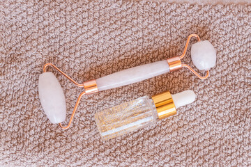 Massage quartz roller for the face of pink natural nephritis with beauty serum oil. Skin care...