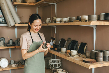 The potter woman checks the finished ceramic dishes. The concept of small business and creativity
