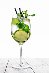 Cocktail in wine glass made with champagne, soda, lime, mint on white background. - obrazy, fototapety, plakaty
