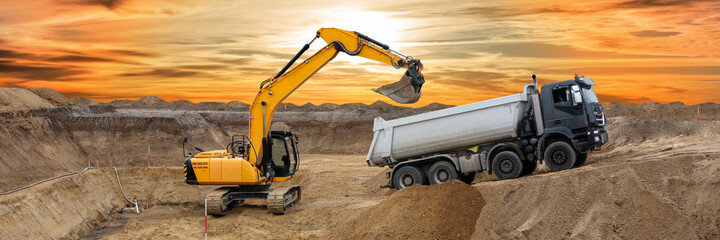 Bagger arbeitet auf einer Baustelle mit dramatischen Wolken
