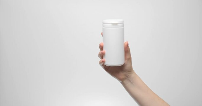 A white plastic jar, a container in a woman's hand. There is a space for advertising or a logo. Template for a commercial product.