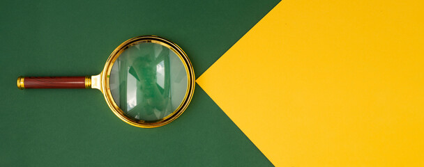 Magnifying lens over green background with yellow paper beam with copyspace for text. Banner with...