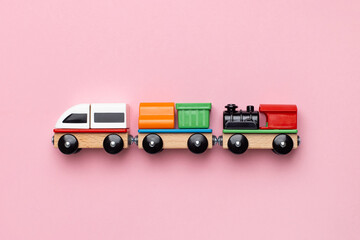 Train children toy, preschool kids game. Locomotive and carriages, wooden colorful blocks construction on pink color background