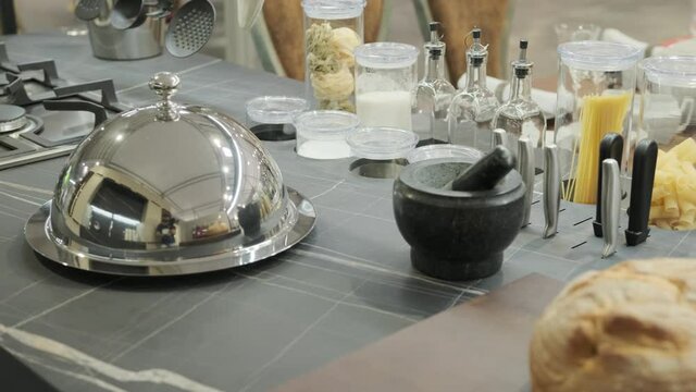 View of the kitchen table with fresh bread and a dish covered with a metal lid