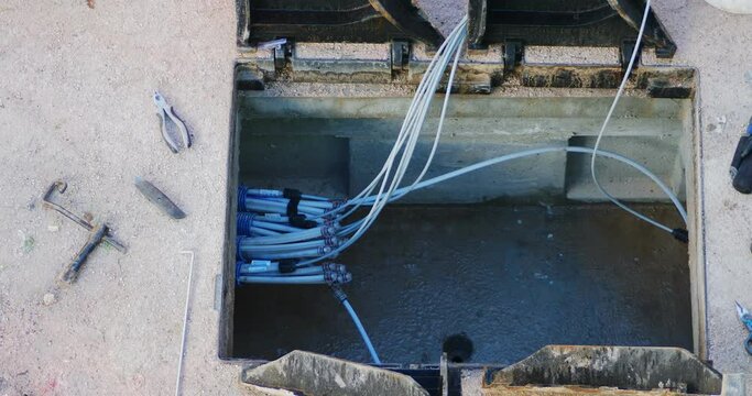 Worker made a break-in with an electric demolition hammer in the reinforced concrete shaft of the fiber optic cable line. Open triangular cast iron manhole covers