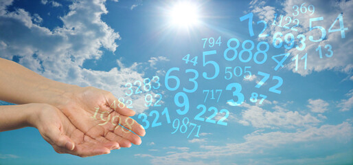 Numerology Concept Sky Website Banner - female cupped hands releasing a stream of transparent numbers tumbling across blue sky and sun shining down background 
