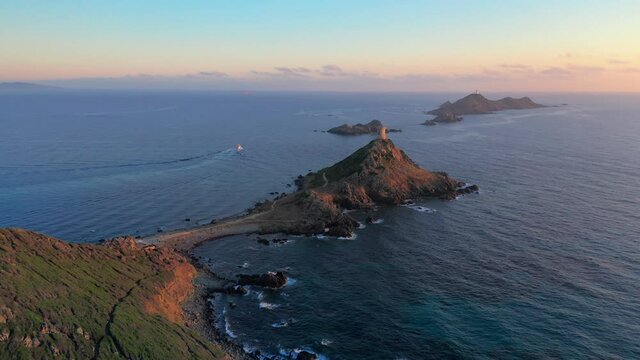 Aerial view lighthouse on mountain rocky hill in sea sunset. Amazing footage of sunrise over the sea during colorful sunset, rocky island,lighthouse on the top of rocky seashore in sundown