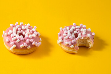 Funny pink donut with marshmallow topping on yellow background