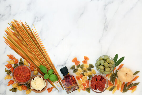 Italian low cholesterol health food ingredients for a healthy diet with tricolour pasta, vegetables, passata, olive oil, parmesan. High in fibre, protein, omega 3 and antioxidants. On marble top view.