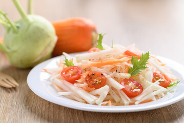 Salad with sliced kohlrabi, carrot, tomato and mizuna leaf on white dish, Vegan food, Healthy eating