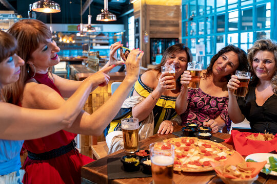 group of mature women is taking a selfie sitting drinking beer