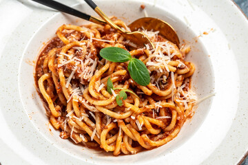 Pasta bolognese with tomato and meat mince sauce served in a plate with parmesan cheese. Traditional italian dish