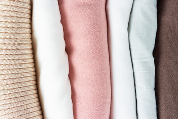 A stack of folded multicolored sweaters close-up top view.