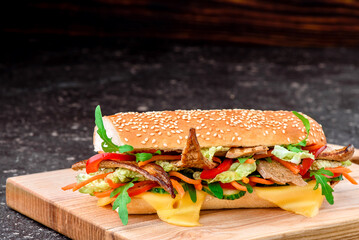 Fresh baguette sandwiches with veal, sliced cheese, tomatoes and fresh lettuce on wooden cutting board. Dark red background. Top view. Space for text