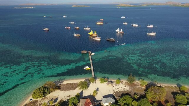 Aerial drone footage of Phinisi traditional boat anchored by the stunning Kanawa island in Komodo area near Labuan Bajo in Flores, Indonesia. Shot with a tilt up motion