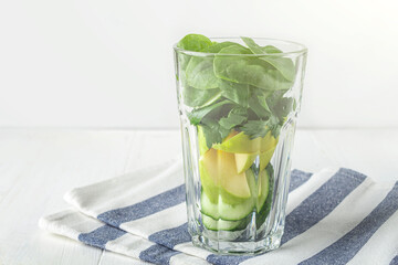 Glass with ingredients for green smoothie: spinach, apple, cucumber. Home cooking. Vegan healthy detox eating, dietary and weight loss drink