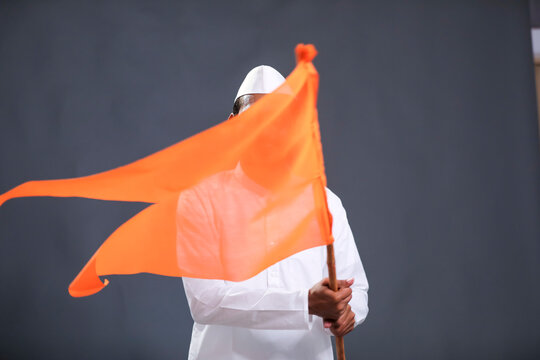 Young indian man (pilgrim) in traditional wear and waving religious flag.