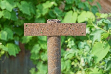 one brown rusty metal pipe with iron plate outdoors on a green background