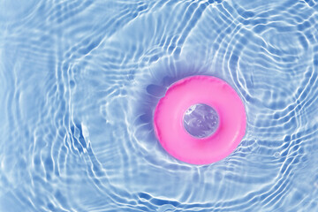Pink pool float ring floating in a refreshing blue swimming pool. Top view
