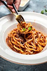 Italian food. Pasta spaghtti with tomato and meat mince sauce served in a plate with parmesan cheese on fork. vertical image