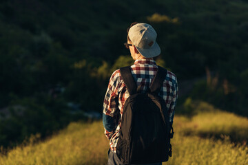 Young traveling man, handsome man in glasses and in a cap, with a backpack, walking in the forests of nature, hiking, active people