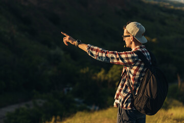 Male tourist on the top of the mountain at sunrise, Young handsome guy with tourist equipment joyfully meets the morning