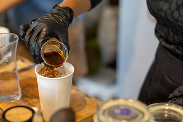 selective focus white paper cups A coffee shop worker wearing black rubber gloves is pouring a shot of black coffee into a paper cup. for customers to buy back