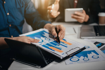 Business, technology and office concept - two businessmen with laptop, tablet pc computer and papers having discussion in modern office.