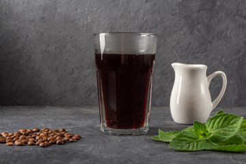 Recipe Ice coffee with mint and milk. Large glass with black coffee. Cool summer drink on dark background in low key. Close up, copy space for text.