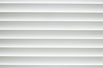 Frontal close-up view of white office shutters made of metal. The curtains cover the window. The strips are horizontally parallel to each other. Texture, background and copy space.